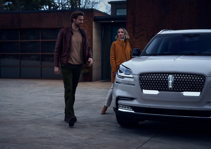 A man and a woman approaching a 2024 Lincoln Aviator® SUV, which illuminates certain lights when they are close | Seekins Lincoln in Fairbanks AK