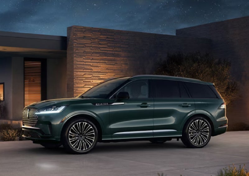 A green 2027 Lincoln Aviator® SUV is parked outside a contemporary home. | Seekins Lincoln in Fairbanks AK