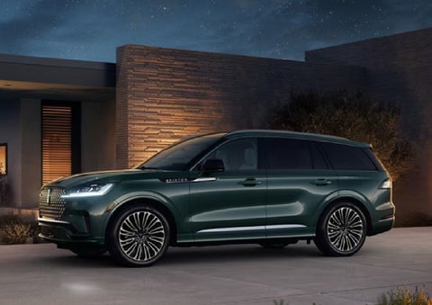 A green 2027 Lincoln Aviator® SUV is parked outside a contemporary home. | Seekins Lincoln in Fairbanks AK