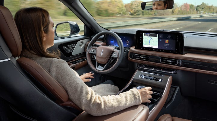 A 2027 Lincoln Aviator® SUV is being driven hands-free on a highway lined with trees. | Seekins Lincoln in Fairbanks AK